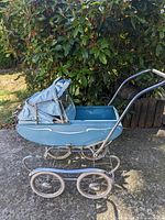 Left side view of blue doll stroller showing canopy, body and wheels