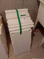 Stacks of white plastic shelf panels with integrated legs, bound together