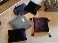 Five pillows and throw blanket displayed on carpet