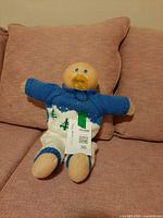 Front view of doll on sofa showing outfit and pacifier