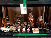Shelf view showing all Santa figurines, sleigh with reindeer, mini Santas, reindeer ornaments, skates and box