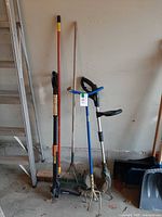 Group of four garden tools standing against wall