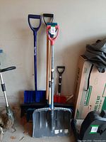 All five snow shovels leaning against wall