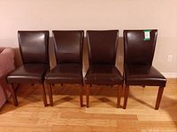 Front view of four brown faux leather dining chairs in a row