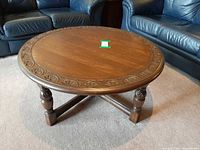 Full view of round carved oak coffee table between sofas