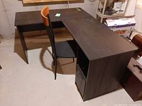 Overall view of L-shaped desk with chair attached, showing desk surface and shelving
