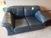Front view of navy blue leather loveseat showing cushions and armrests