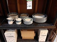 Full set on shelving showing plates, bowls, creamer, sugar bowl and original boxes