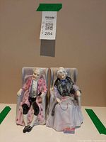 Front view of both Darby and Joan figurines in chairs