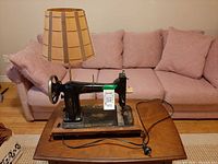 Full view of sewing machine lamp on table, showing shade, base, and cord