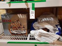 Boxed village scene and bagged Santa balloon on shelf