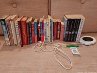 Row of 23 books with mug warmer and power cord on sofa