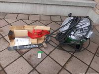 Hedge trimmer boxed beside broadcast spreader