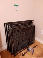 Stacked foldable metal playpen panels with stakes bag visible