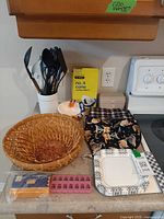 Overall lot view showing utensils in holder, baskets, coffee filters, recipe box, disposable plates, pill organizer, fabric items, sealed package