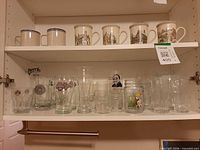 Full view of cupboard shelves showing ceramic mugs and assorted glassware