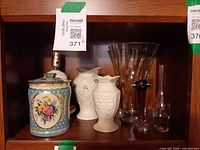 Overall view of tin, two white vases, large clear vase, amber bud vase, clear bottle and lamp socket