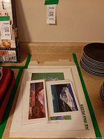 Stack of prints and two postcard-sized landscape photographs on countertop