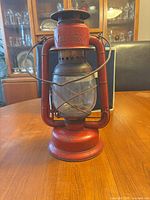Front view of red Beacon kerosene lantern showing glass globe, wire guard, burner, embossed brand