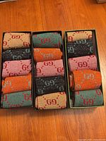 Three open boxes showing folded metallic GG socks in assorted colours