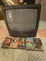 Front view of Sansui 19" TV/VCR combo with five VHS tapes laid in front