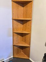 Full view of tall corner bookshelf showing wood grain and shelves