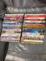 Two stacks of 34 DVD cases on leather surface; spines facing up showing assorted movie titles