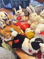 Group of plush toys including dog with heart, rabbits, bears and heart pillow