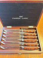 Open box showing six knives in fitted slots, interior branding visible