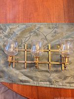 Front view of brass wall sconce with three glass cups attached, frame horizontal