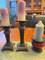 Two tall column candle stands and one pedestal holder with candles