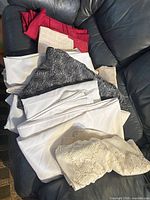 Pile of assorted folded tablecloths on sofa