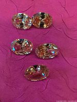 Five oval faceted champagne rhinestones grouped on magenta fabric