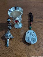 Three Chinese silver-tone metal items on wood surface