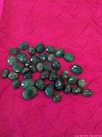 Group view of all green aventurine loose stones on pink fabric