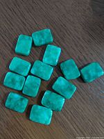 All 10 rectangular green stones spread out on wood surface