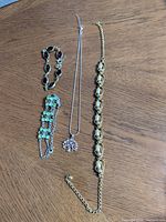 Group shot of necklace and three bracelets aligned on table