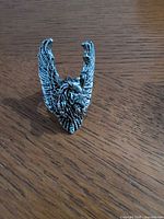 Front view of silver-tone eagle wings ring standing upright