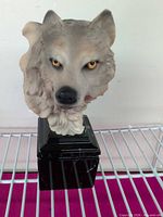 Front view of wolf head sculpture on pedestal