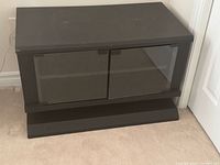 Front view of black MDF TV stand, closed glass doors visible