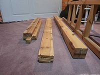 bundled pine bed posts, rails, ladder pieces laid on carpet