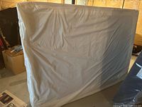 Full view of mattress standing upright in protective cover