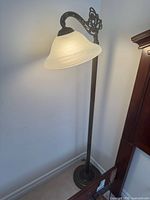 Full view of bronze metal floor lamp with frosted glass shade