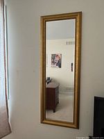 Gold framed full-length mirror mounted on wall