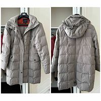 Front view of light gray hooded puffer coat showing zipper, snap placket and pockets