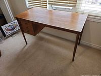 Overall view of teak veneer desk showing top, legs, drawer bank