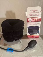 OTC black velour inflatable cervical traction collar, hand pump bulb with tubing and blue valve clip, original branded box