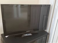 Front view of Samsung 32-inch TV on stand with remote on base