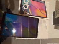 Front of Samsung Galaxy Tab A powered on over retail box