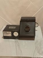 Samsung Galaxy Watch in presentation cradle beside original box